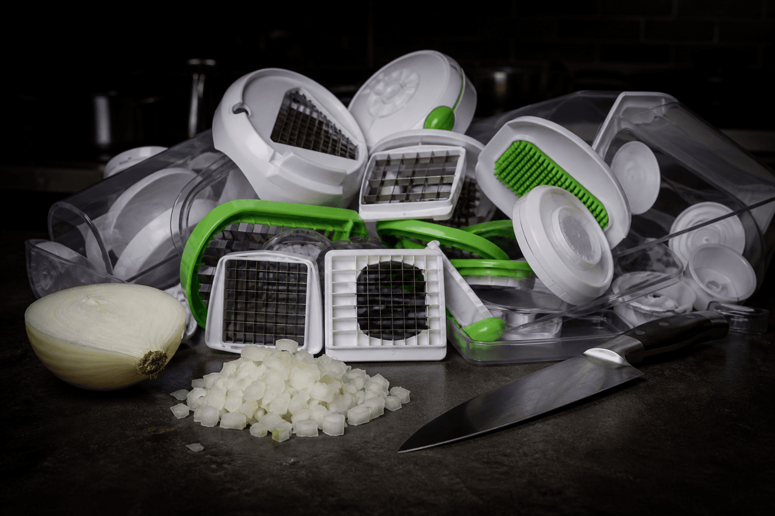 Plastik-løghakker i mange dele ved siden af en kniv og hakket løg