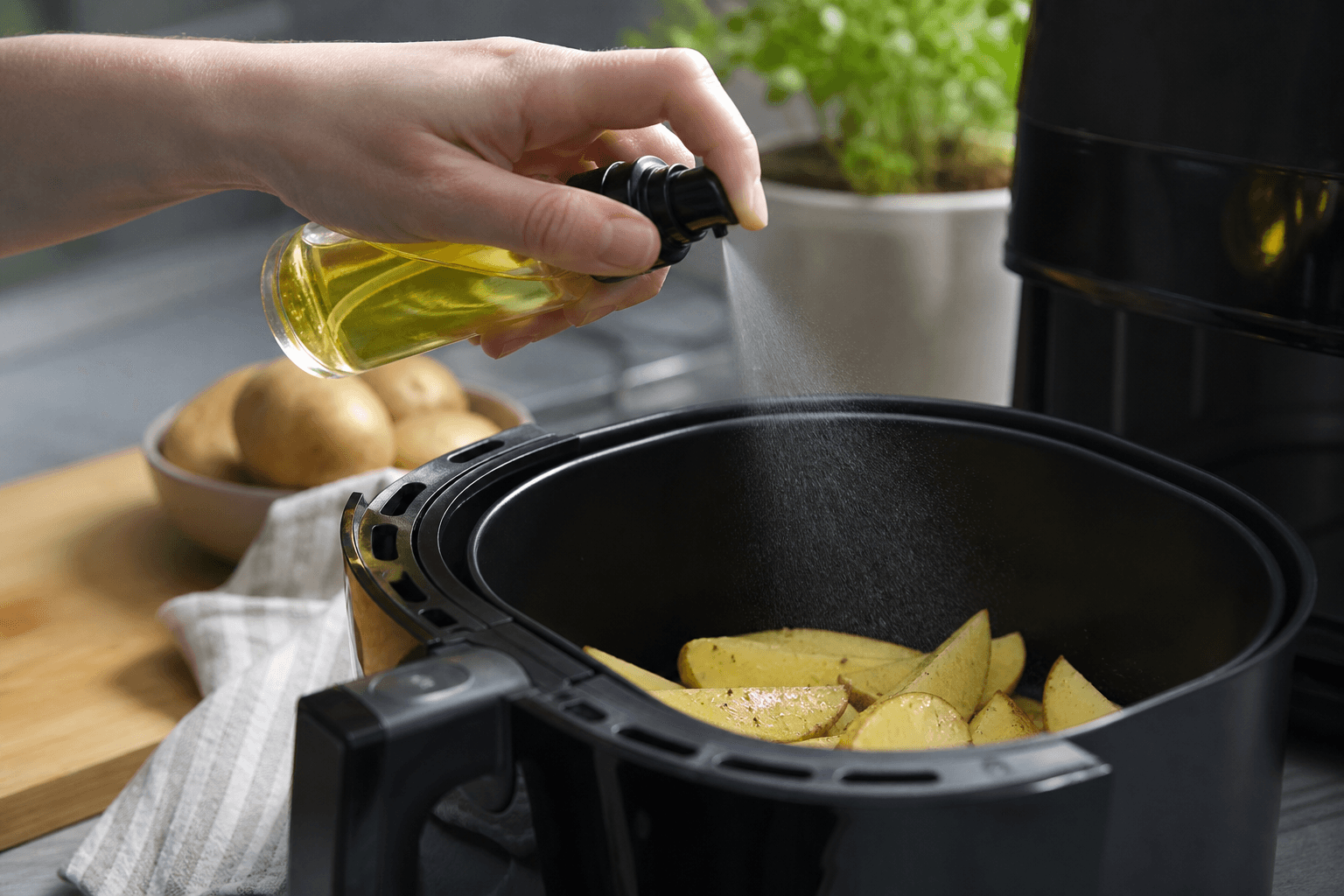 Oliesprayflaske der forstøver olie over airfryer-kurv
