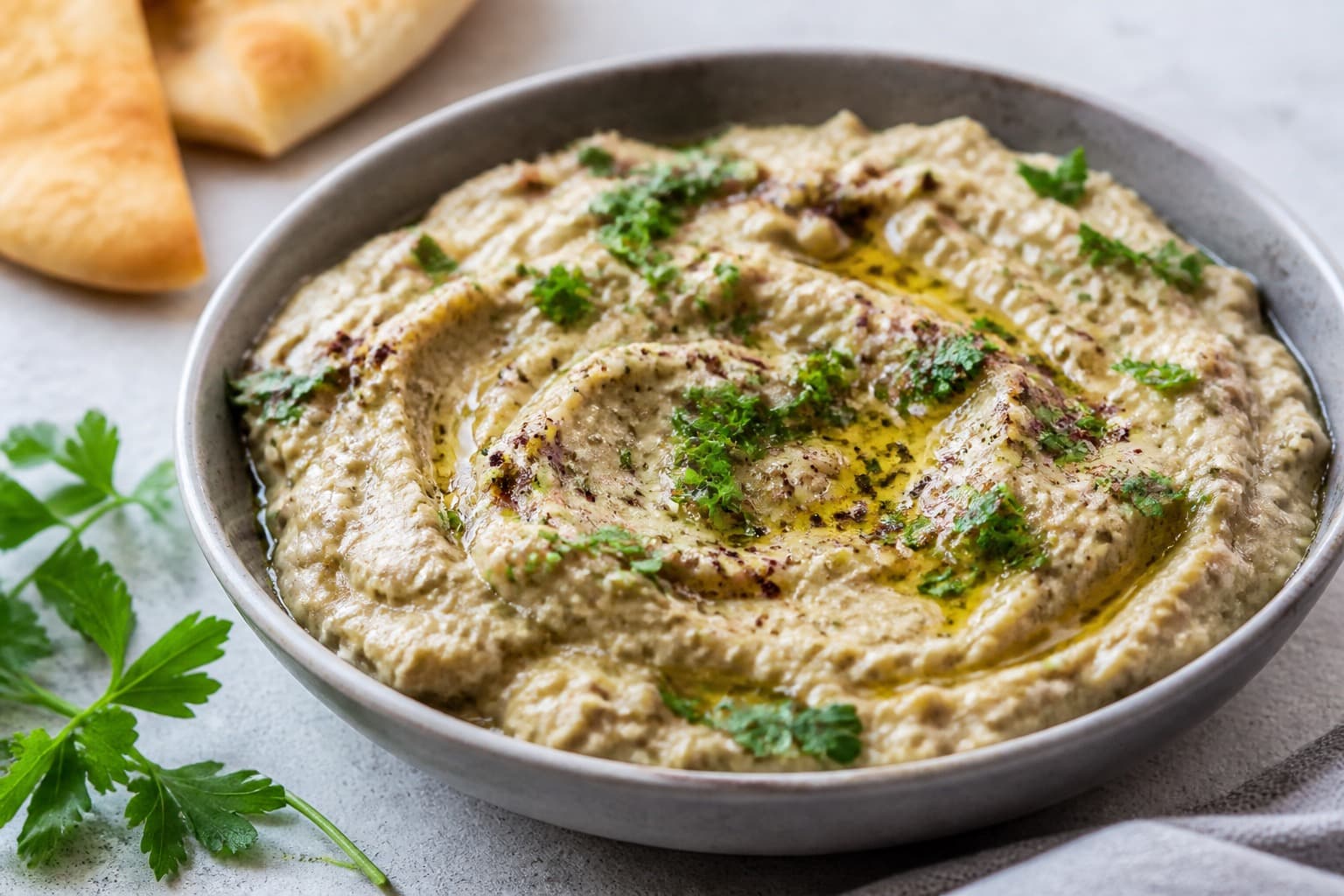 Skål med baba ganoush dryppet med olivenolie og granatæblekerner