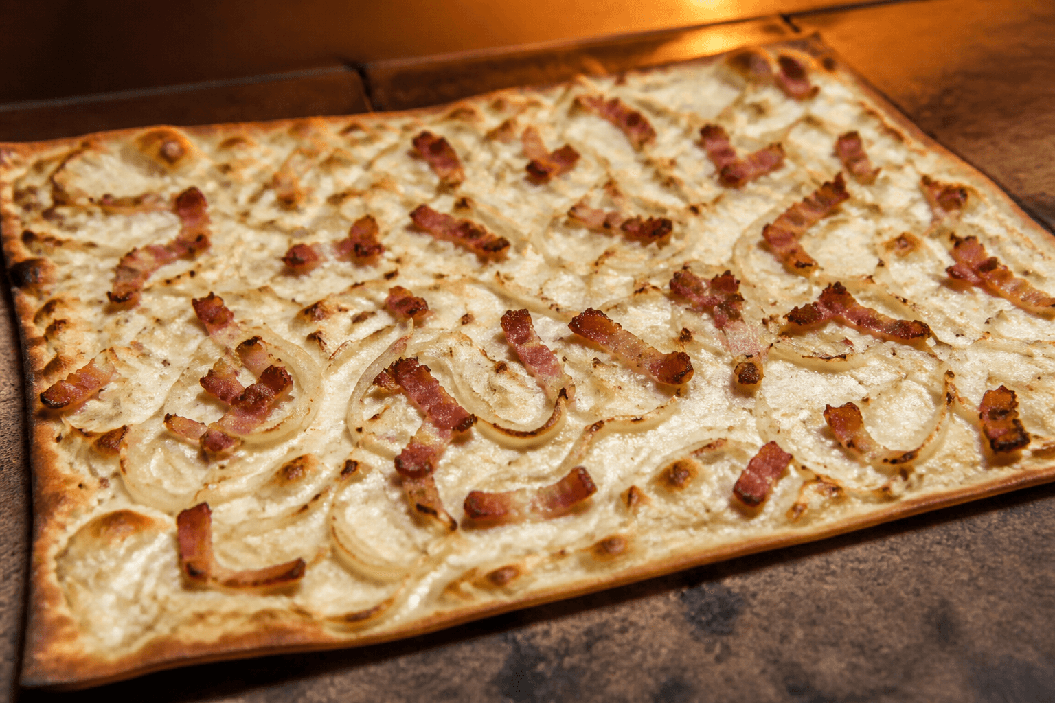 Flammkuchen med crème fraîche, løg og røget bacon